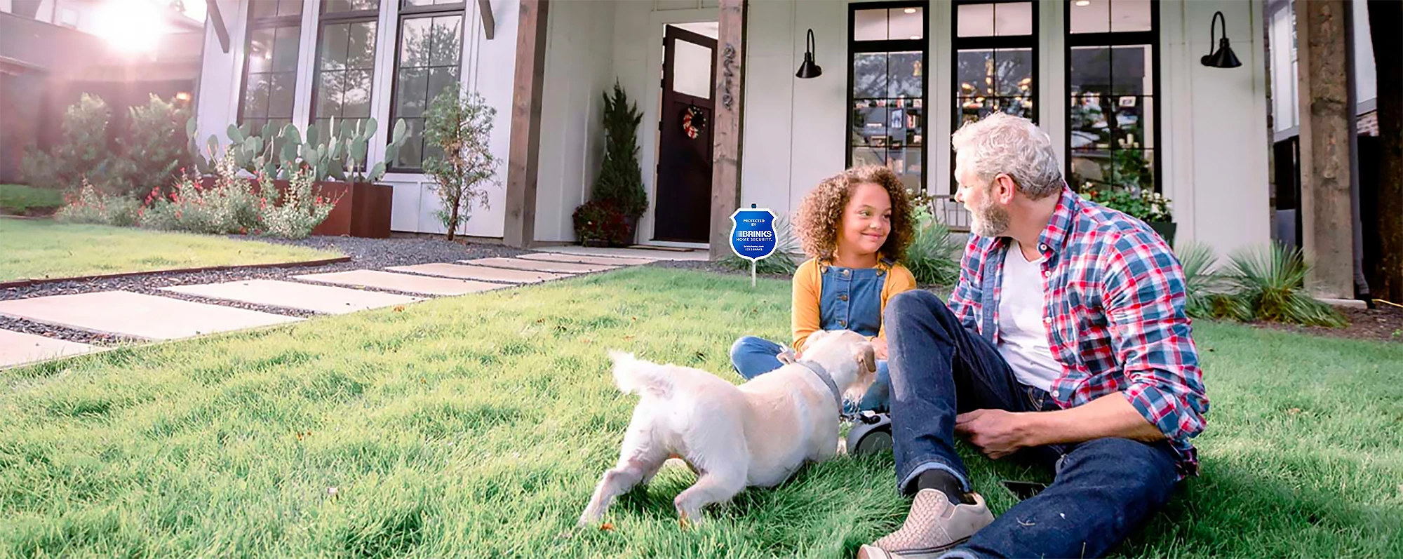 Father and daughter playing with their dog in the front yard